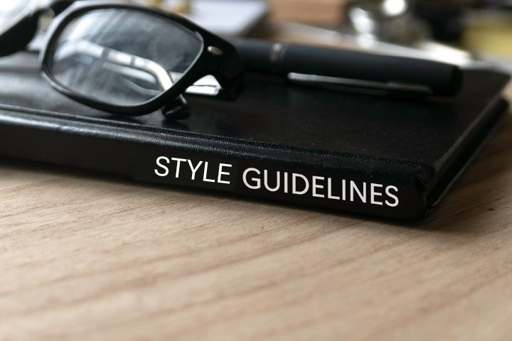 Eye glasses and a pen sitting on top of a style guide.