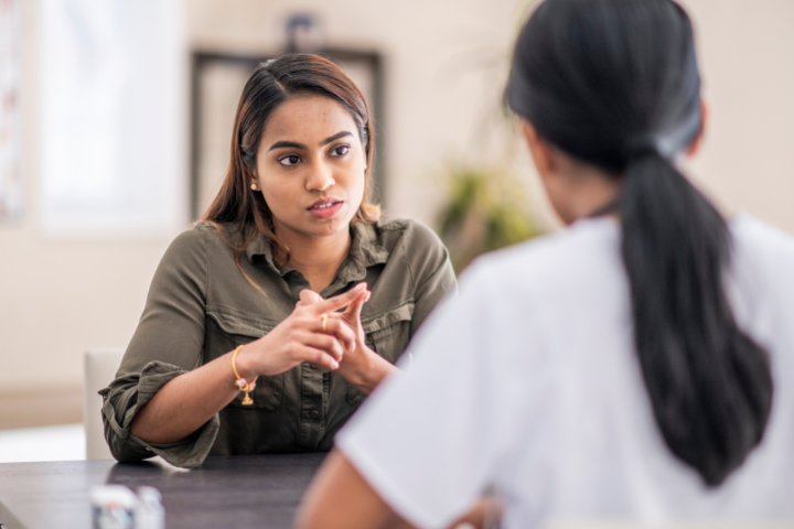 Two people sitting at a table looking at each other.