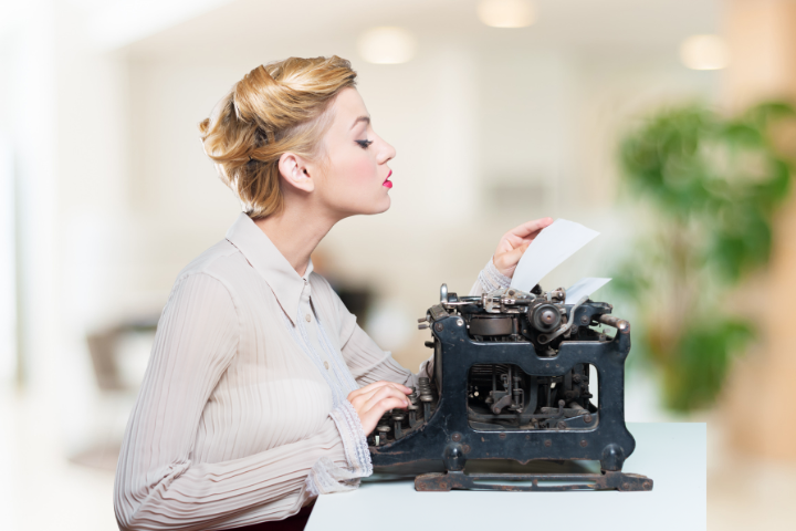 A person sitting at an old typewriter.