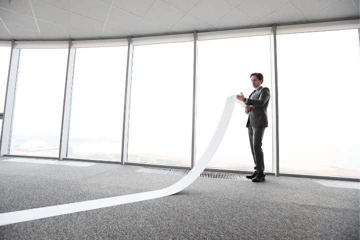 A person standing with a very long list written on paper.