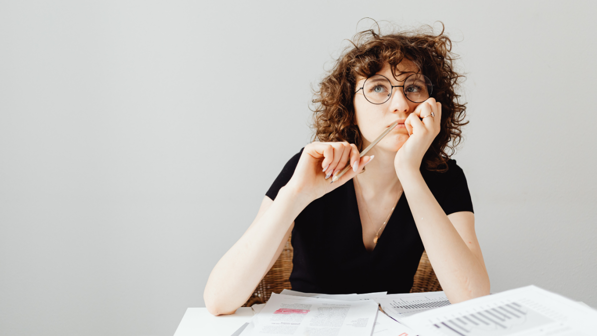 woman sitting at her desk thinking about which word she needs to use, its or it's