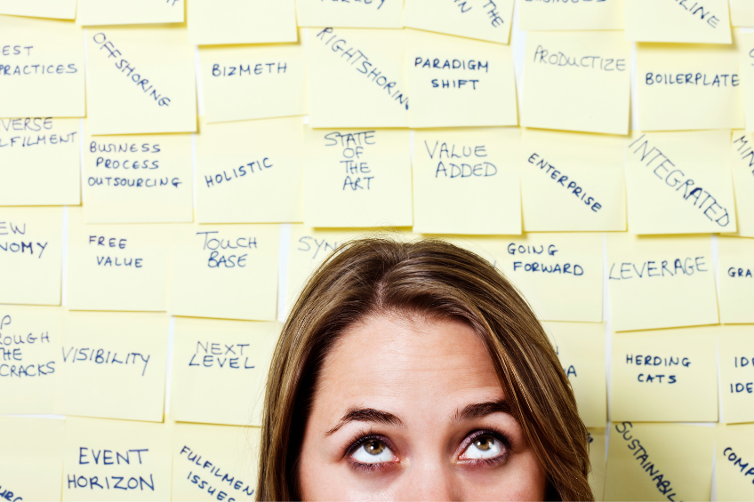 woman looking confused in front of a wall full of sticky notes with various jargon on each one