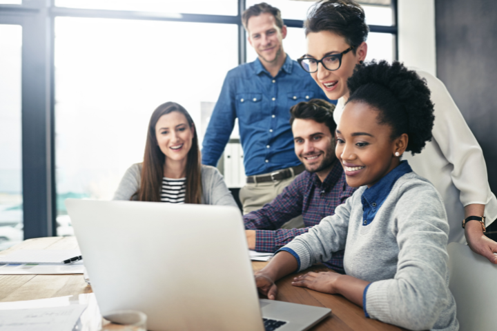 Happy people working together around a computer.