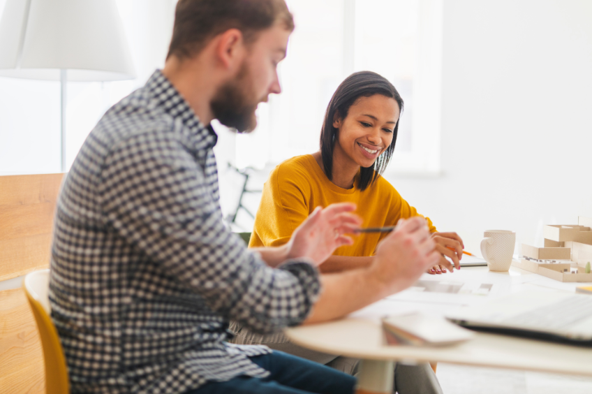 manager sitting next to his employee editing documents alongside her