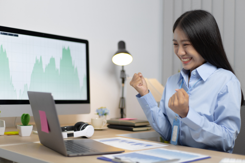 Excited women sitting at her desk, after discovering her proposal was accepted