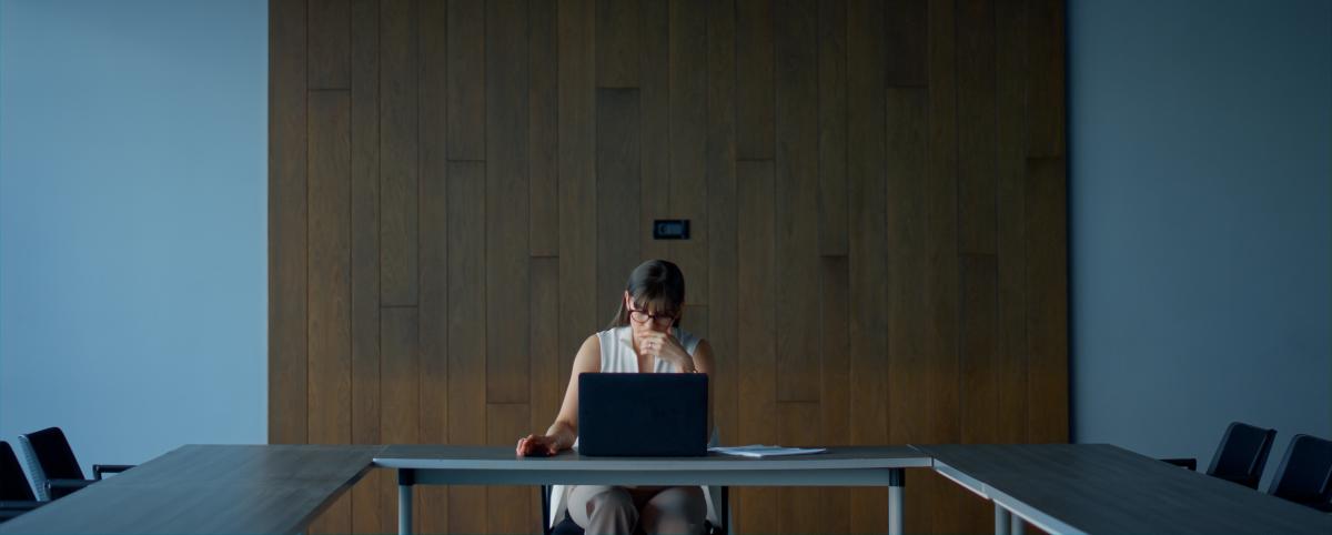 woman sits alone at a board room table 