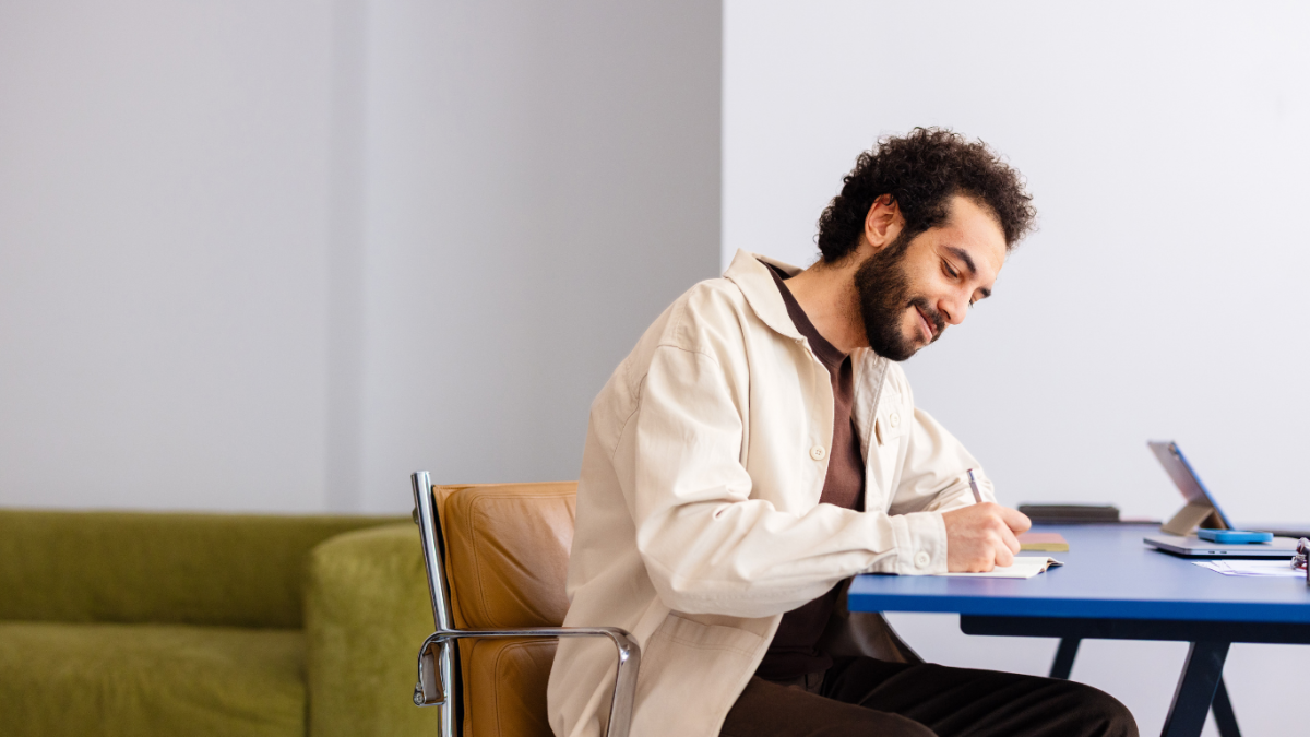 man writing at a desk with a pen